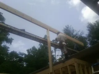 Carpenter setting a ridge beam over a new addition frame — Ice Dam Removal by Roofing Brothers in Rush