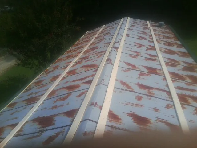Rusted metal roof panels with new wood purlins before replacement — Storm Damage Roof Repair in Rush by Roofing Brothers
