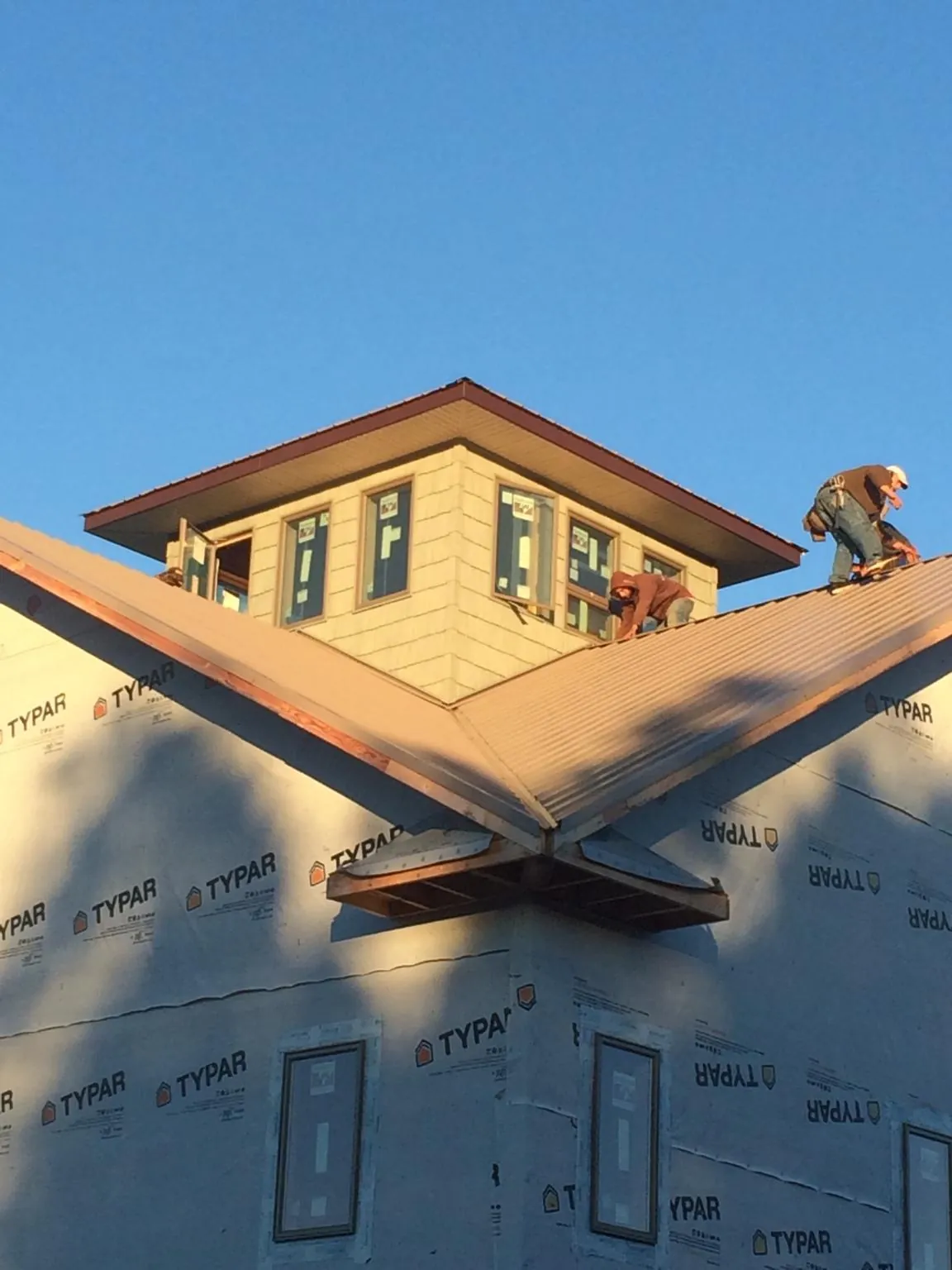 Roofers working around a rooftop cupola on a new metal roof at sunset — Roof Waterproofing in Rush by Roofing Brothers